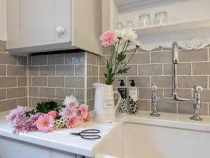 un mostrador de cocina con un jarrón de flores en un fregadero en 2 Bed in Minchinhampton 77489 en Minchinhampton