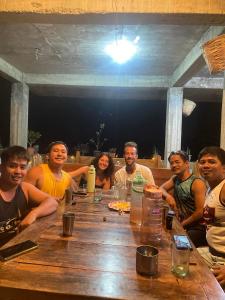 een groep mensen die rond een houten tafel zitten bij Batad Pension and Restaurant in Banaue