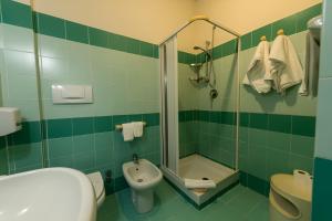 un bagno piastrellato verde con lavandino e doccia di Hotel Baia Turchese a Lampedusa