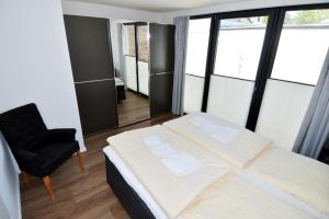 a bedroom with a large bed and a chair at Fischerdorf No 26 in Heiligenhafen