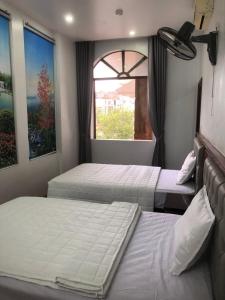 dwa łóżka w pokoju z oknem w obiekcie Hotel Nam Sơn Tân Dương w mieście Hoàng Mai
