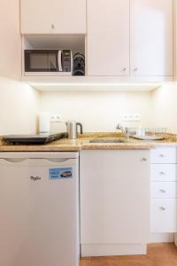 a kitchen with white cabinets and a microwave at Victus Apartamenty, Apartament Garden in Sopot