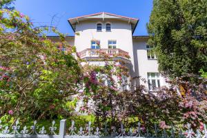a white building with a balcony and trees at Victus Apartamenty, Apartament Garden in Sopot