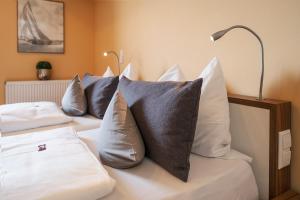 a bedroom with two beds with pillows and a lamp at Boutiquehotel zur Winzerstube - Adults Only in Hagnau