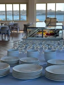 un buffet avec des assiettes blanches et des verres sur une table dans l'établissement Hotel Baia Turchese, à Lampedusa
