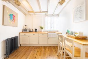 cocina con armarios blancos y suelo de madera en The Art Studio en Henley in Arden