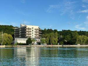 a building on the shore of a body of water at Világos Hotel Balatonvilágos in Balatonvilágos