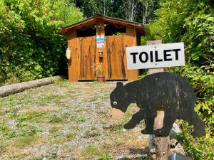 Ein Schild, auf dem steht, Toilette mit einem Bären drauf. in der Unterkunft So Damn Lucky Glamping in Ucluelet