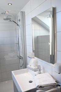 ein weißes Bad mit einem Waschbecken und einer Dusche in der Unterkunft Gästehaus Zum Stehling in Monschau