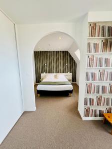 a bedroom with a bed in a room with bookshelves at Le Clos Normand in Saint-Aubin-sur-Mer