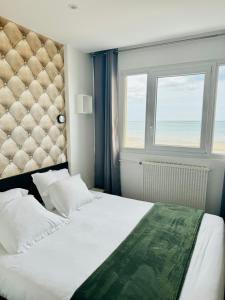 um quarto com uma cama grande e uma janela em Le Clos Normand em Saint-Aubin-sur-Mer