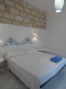 Cama blanca en habitación con pared de ladrillo en Il Cortile Di Eolo, en Marettimo