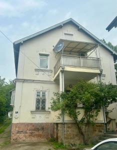 Casa blanca con balcón en la parte superior. en Apartment in Vrnjacka Banja, en Vrnjačka Banja