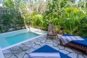 Un patio trasero con piscina, una silla y un columpio. en Exquisite Tulum jungle condo w/private pool!, en Tulum