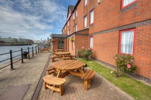 a row of wooden tables and benches next to a brick building at The Dolby Hotel Liverpool - Free city centre parking in Liverpool