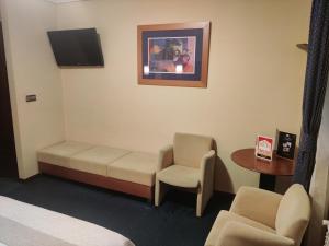 um quarto com uma cama, uma cadeira e uma televisão em Motel Punta Cana em Santiago de Compostela