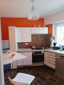 - une cuisine avec des placards blancs et un mur orange dans l'établissement Le Seventies, à Dunkerque 8 autres photos