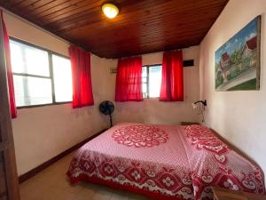 1 dormitorio con cama roja y cortinas rojas en Caribbean Queen en San Andrés