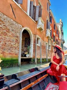 Una mujer con un vestido rojo sentada en un edificio en Locanda Cà Del Console, en Venecia