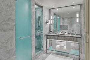 uma casa de banho com uma cabina de duche em vidro e um lavatório. em St. Regis Aspen Resort em Aspen
