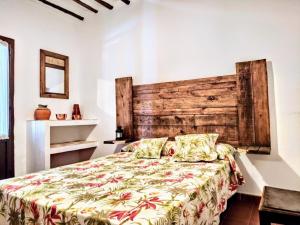 a bedroom with a bed and a wooden headboard at Casa Rural Patio Andaluz in Campo-Nubes