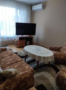 a living room with a coffee table and a flat screen tv at Belatrix Varna Apartment in Varna City
