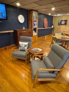 a waiting room with chairs and tables and a clock at Skyline Village Inn in Spruce Pine
