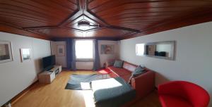 a living room with a red couch and a wooden ceiling at Haus Basilea in Wolfhalden 