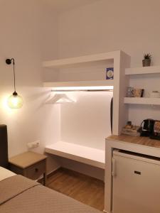 a room with a bed and a kitchen with a shelf at Litsa Studios in Patitiri