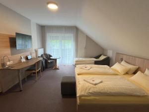 a hotel room with two beds and a desk at Hotel am Steinertsee - Kassel-Ost in Kaufungen