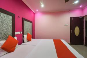 a bedroom with a bed with pink and orange pillows at Hotel Kohinoor in Durgāpur