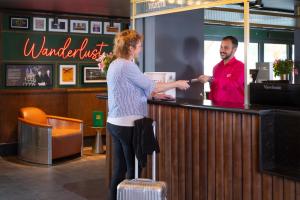 a woman standing at a bar with a man standing behind a counter at ibis Styles London Gatwick Airport in Crawley