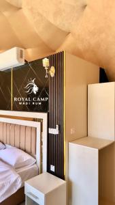 um quarto com uma cama e uma placa na parede em ROYAl WADI RUM CAMP em Wadi Rum
