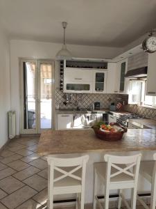 a kitchen with white cabinets and a counter with chairs at La Casetta Bianca in Follonica