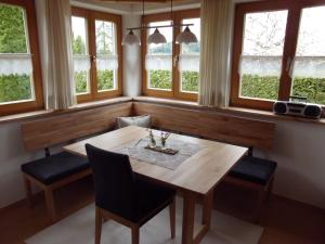 una sala da pranzo con tavolo, sedie e finestre di Ferienwohnung Annele a Hittisau