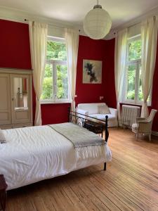a bedroom with red walls and a bed and a couch at B&B Le Manoir de la Douve in Heuvelland
