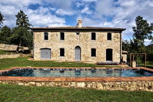 ein Steinhaus mit einem Pool davor in der Unterkunft Tenuta San Galgano in Monticiano