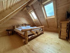 a bedroom with a bed in a wooden attic at LA CABANE in Comandău