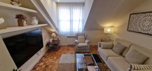 a living room with a couch and a tv at La Buhardilla de la Escalerona - 2 Hab - VUT-4354-AS in Gijón