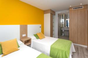 sypialnia z 2 łóżkami i żółtą ścianą w obiekcie Aparthotel Acuasol w mieście Peñíscola