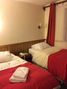 ein Hotelzimmer mit 2 Betten und roten Vorhängen in der Unterkunft Hotel Condor de Plata in Punta Arenas