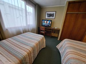 ein Hotelzimmer mit 2 Betten und einem TV in der Unterkunft Hotel Condor de Plata in Punta Arenas