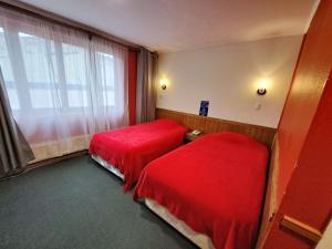 una camera d'albergo con due letti e una finestra di Hotel Condor de Plata a Punta Arenas