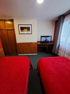 una camera d'albergo con due letti e una televisione di Hotel Condor de Plata a Punta Arenas