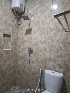 uma casa de banho com um WC e uma parede em azulejo em Sulfat indah Home Stay Syariah em Ngadipuro