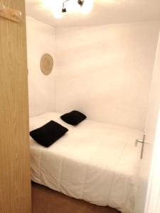um quarto com uma cama branca com almofadas pretas em Appartement confortable Saint Lary village em Saint-Lary-Soulan