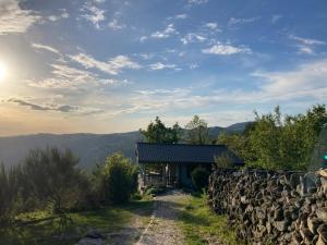 a stone wall next to a building with a stone fence at Private Mountain Log Cabin with amazing panoramic sunset views at small scale nature resort in Cabeceiras de Basto
