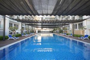 a large swimming pool in a building with chairs at Silk Valley - Furnished Studio With Balcony in Abu Dhabi