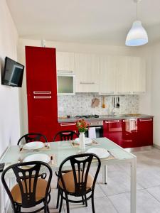 une cuisine avec des placards rouges, une table blanche et des chaises dans l'établissement Affacciati sulle Eolie Appartamenti sul Lungomare Patti Marina, à Patti