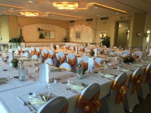 a banquet hall with white tables and chairs with bows at Hotel Görres in Wachtberg